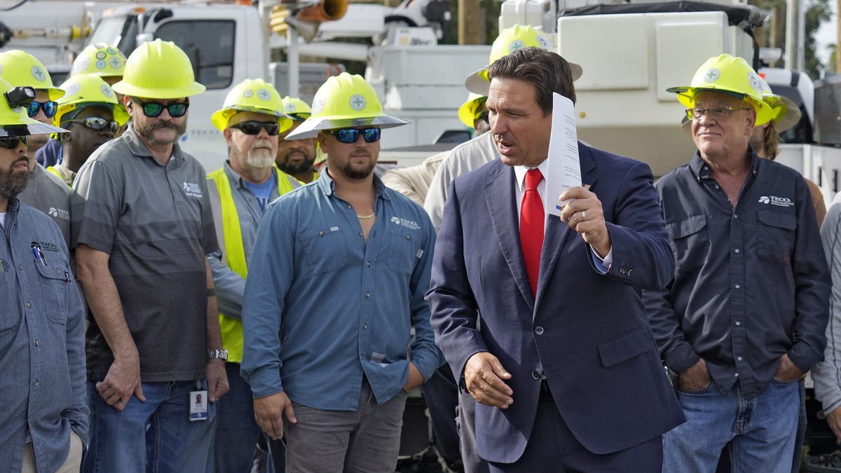 El gobernador de Florida, Ron DeSantis, segundo por la derecha, habla con los operarios del tendido eléctrico antes de una rueda de prensa, el miércoles 25 de septiembre de 2024, en las oficinas de la Tampa Electric Company en Tampa, Florida, mientras la tormenta tropical Helene, que se espera que se convierta en huracán, avanza hacia el norte por la costa de México en dirección a EEUU.