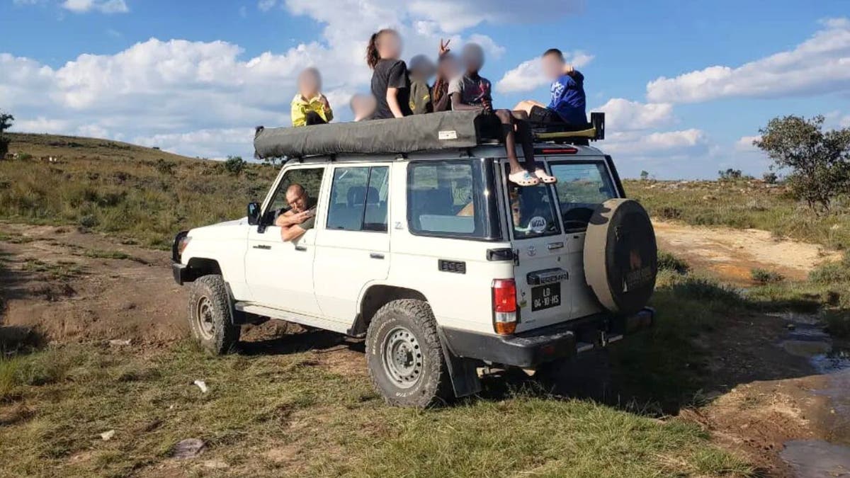 Pastor Beau Shroyer in a jeep with children sitting on the vehicle's roof.