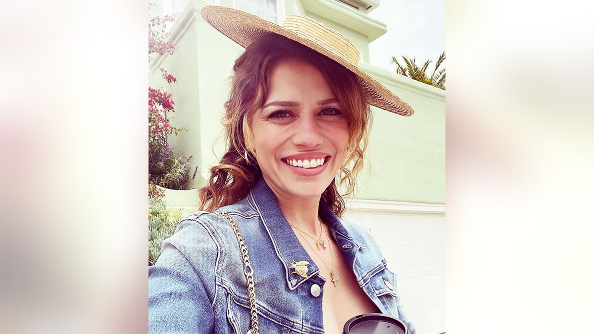 Bethany Joy Lenz in a denim jacket and hat lies askew on her head