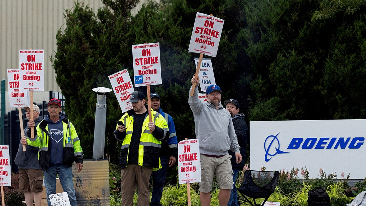 Sindicalistas em greve ao lado de placa da Boeing