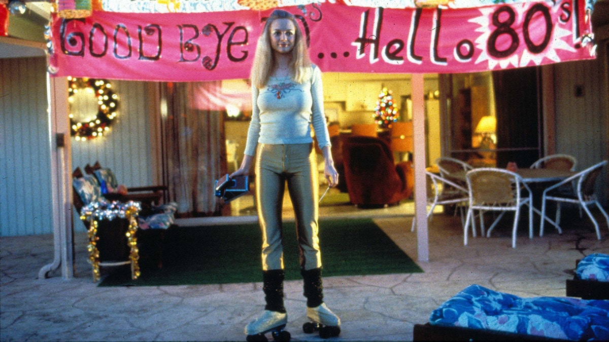 Heather Graham in a scene from Boogie Nights wearing roller skates at a welcome to the 80s party