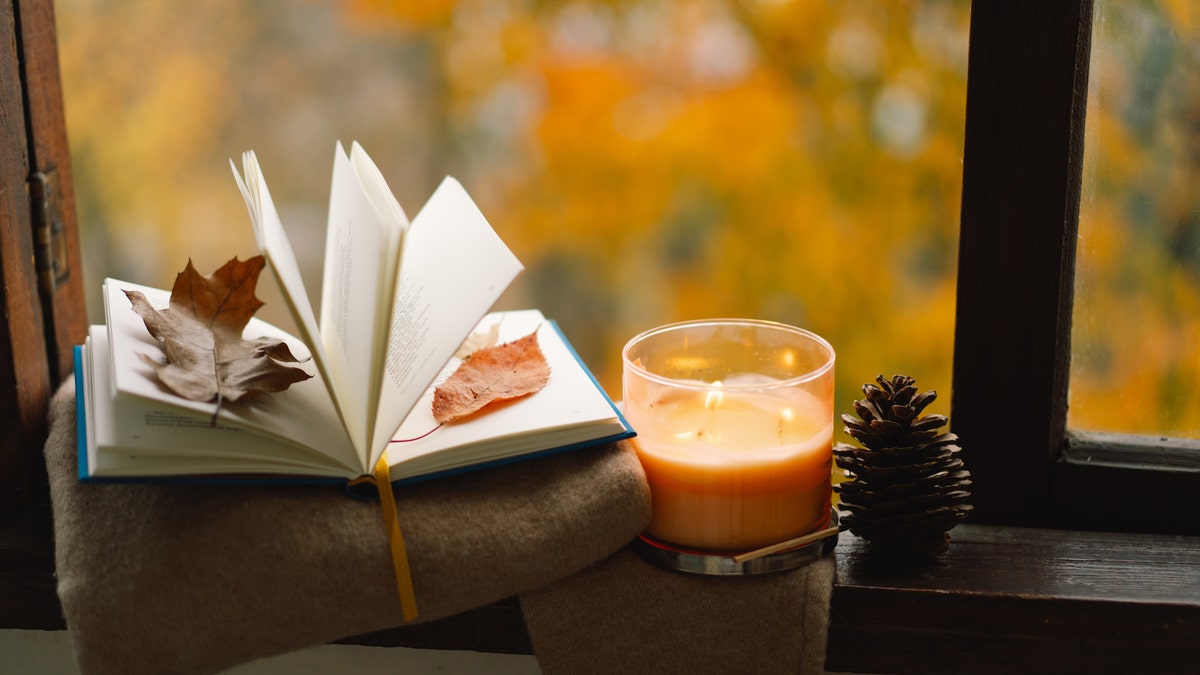 A book, a candle and fall weather in the background