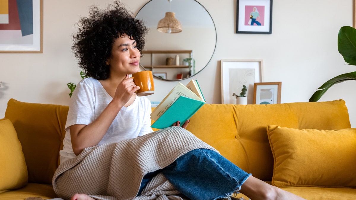 Una mujer con una taza de café y un libro.