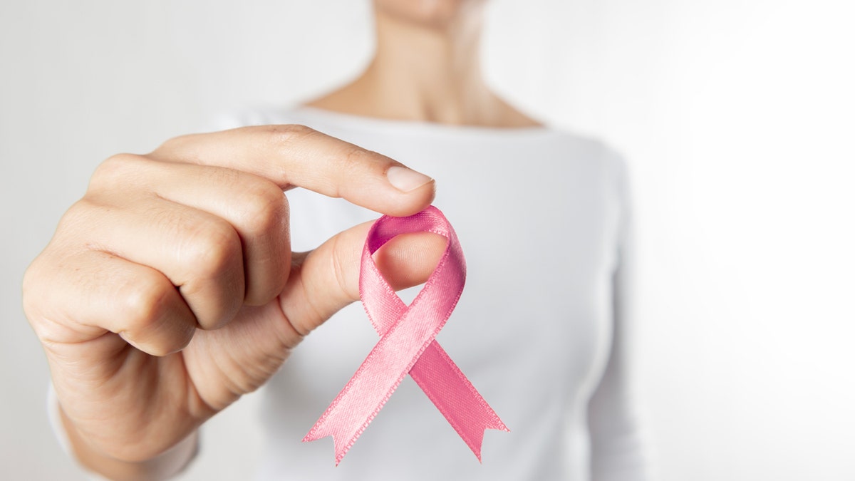 Una mujer sosteniendo una cinta de cáncer de mama.