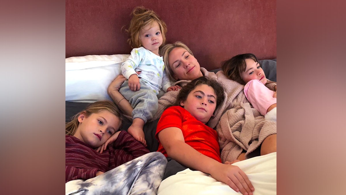 Sharna Burgess lies down on the bed surrounded by her four kids