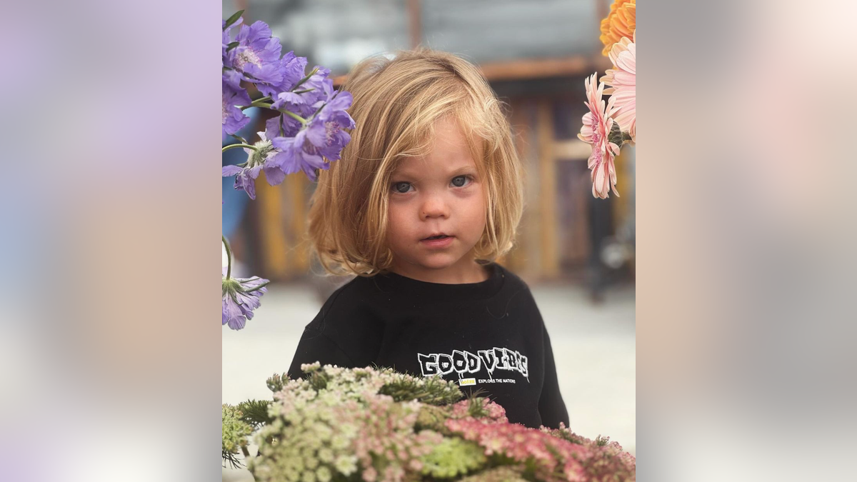 A picture of a little boy in a black shirt with long blonde hair