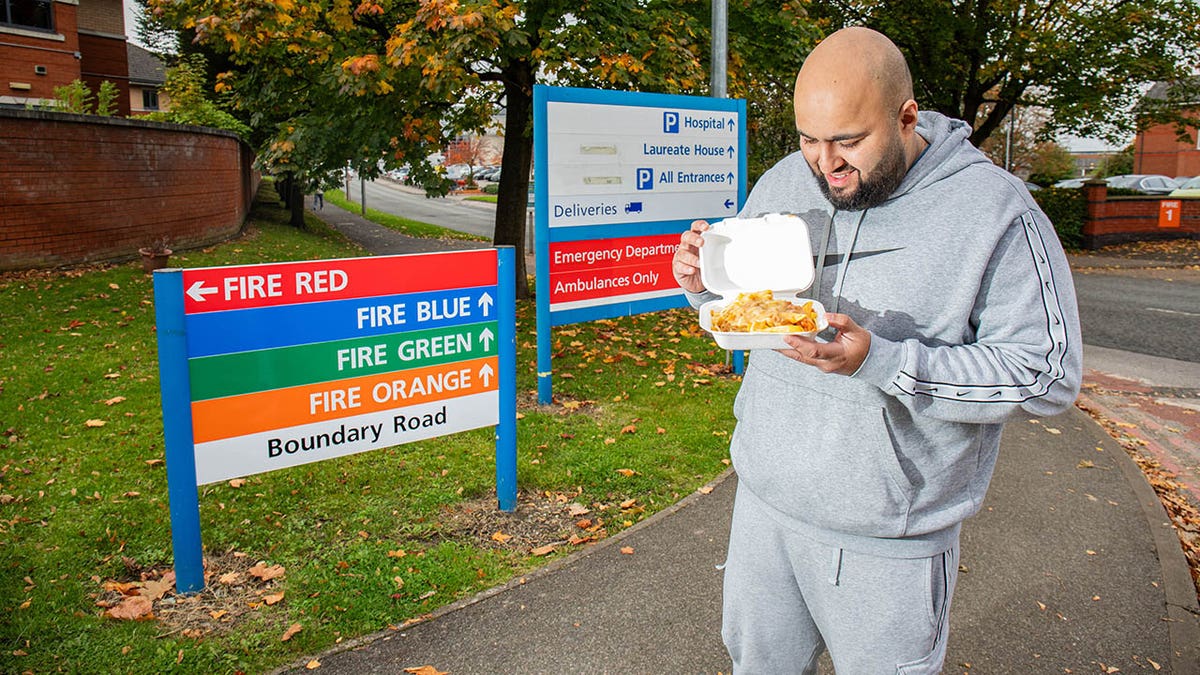 Un hombre sosteniendo comida afuera de un hospital del NHS.