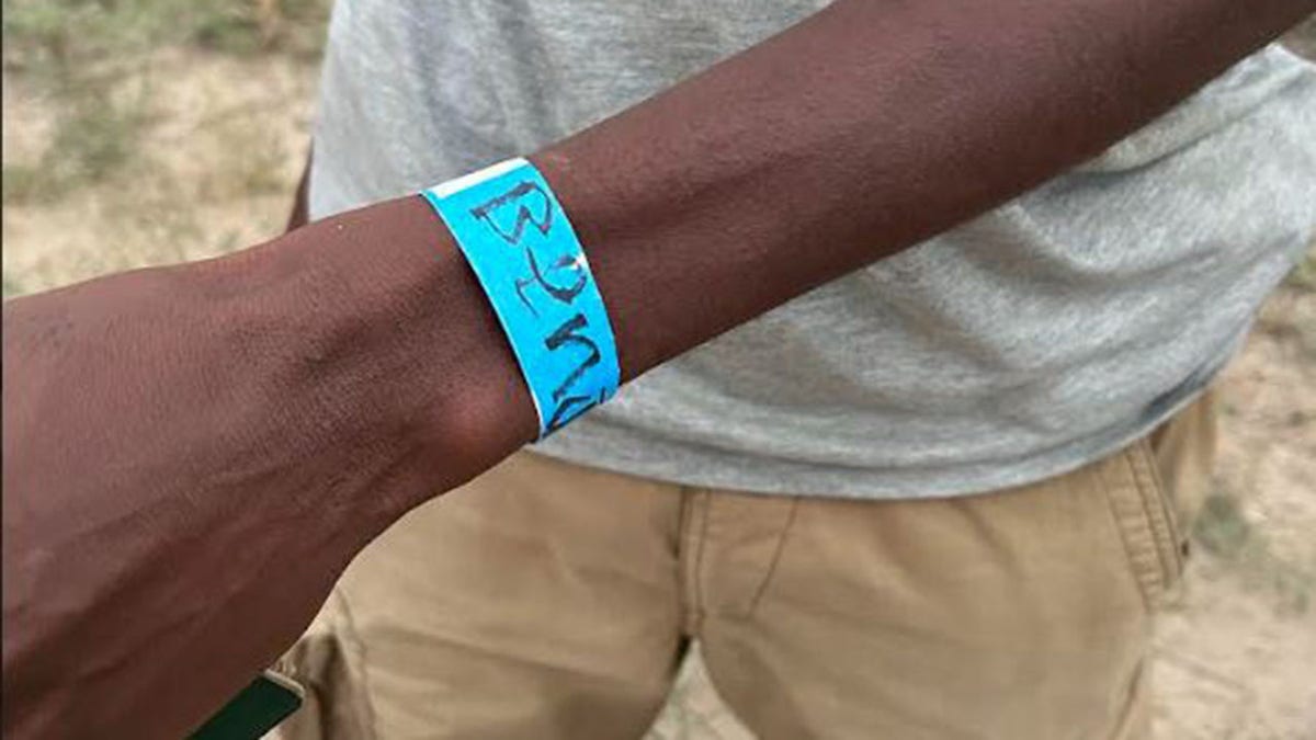 Migrants pinch a bluish bracelet