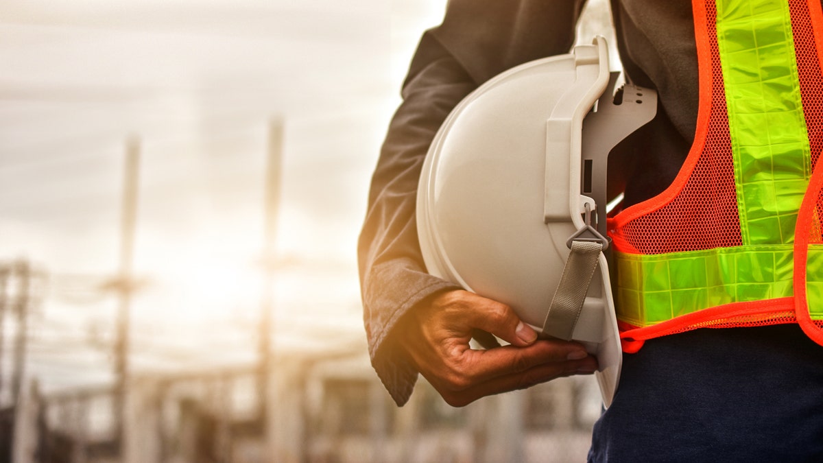 Construction worker holding hard hat under arm