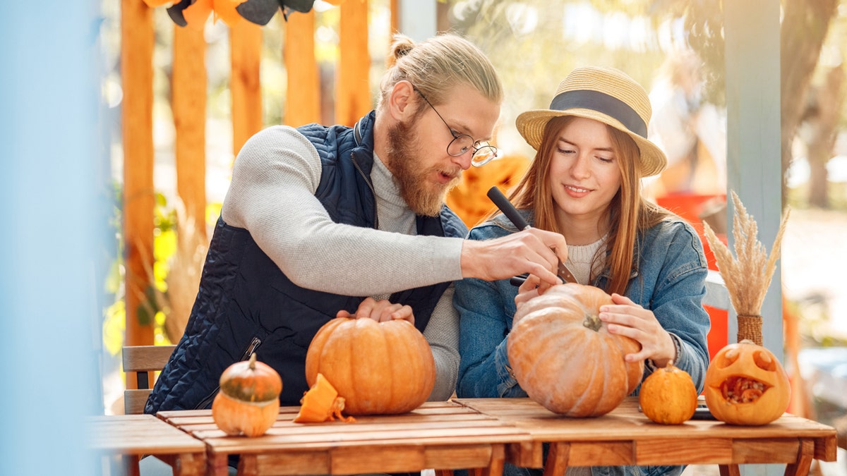 A couple carving pumpkins