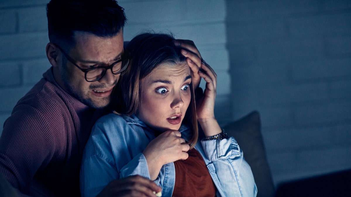 Un marido y una mujer están viendo una película de terror.