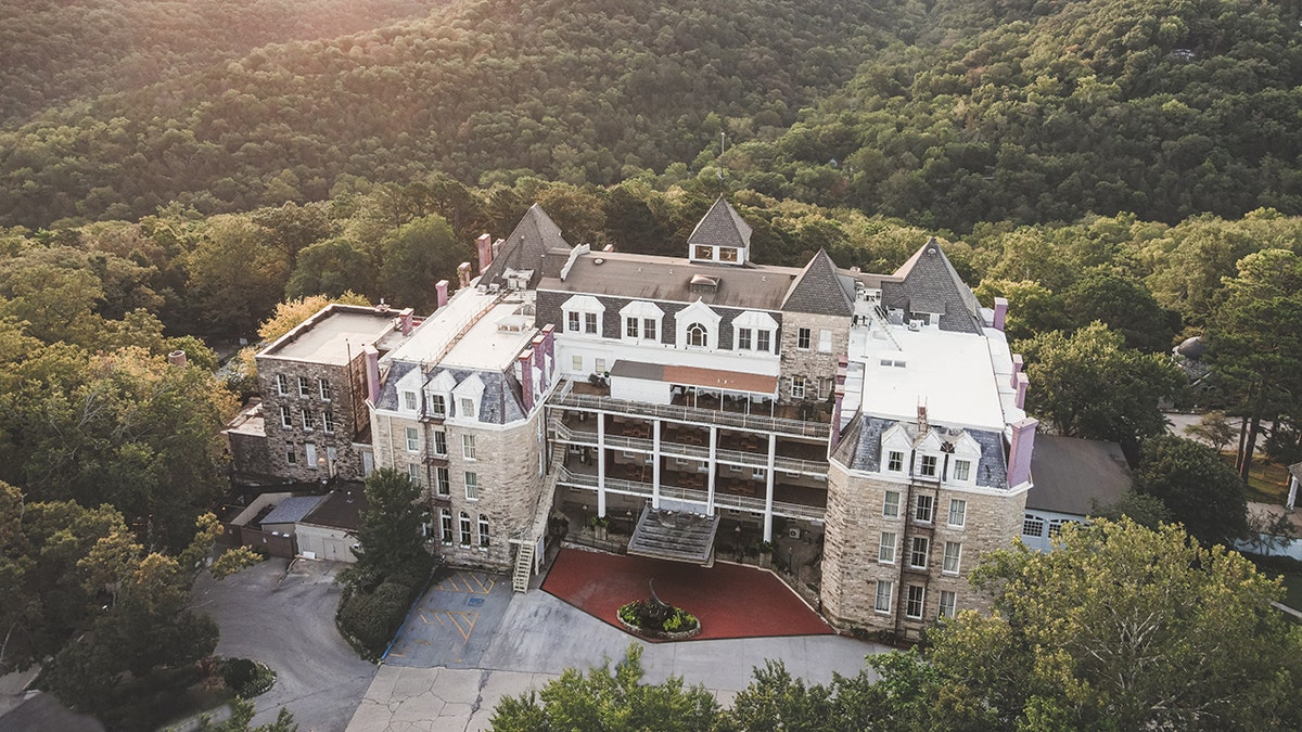 Overhead exterior view of Crescent hotel, seen atop hill in in Eureka Springs, Arkansas, surrounded by forest.