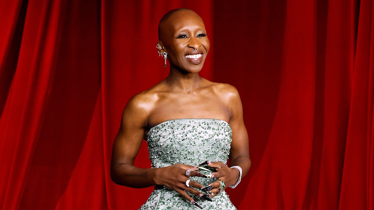 Cynthia Erivo smiling in a light green strapless dress