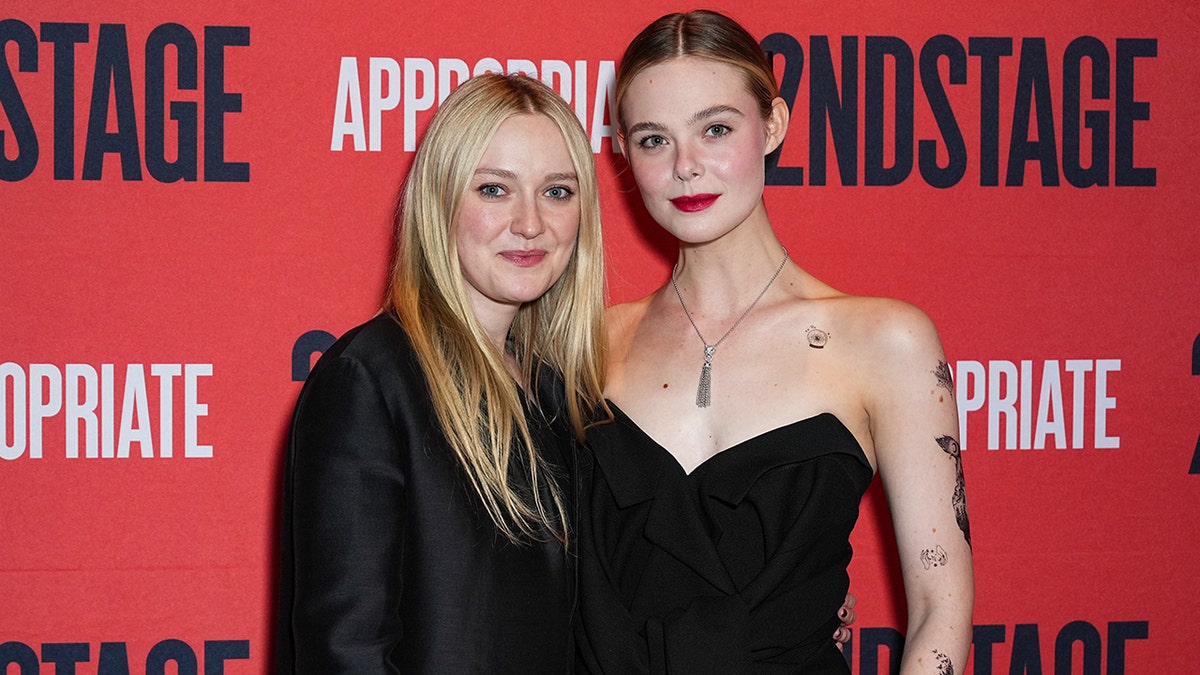 Dakota Fanning sorri suavemente em uma jaqueta preta enquanto posa com a irmã Elle Fanning em uma roupa preta sem alças