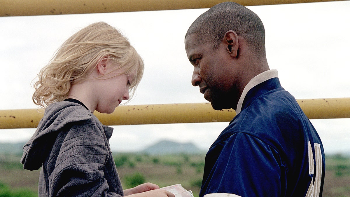 Dakota Fanning and Denzel Washington both looking down at something in character on 'Man on Fire'