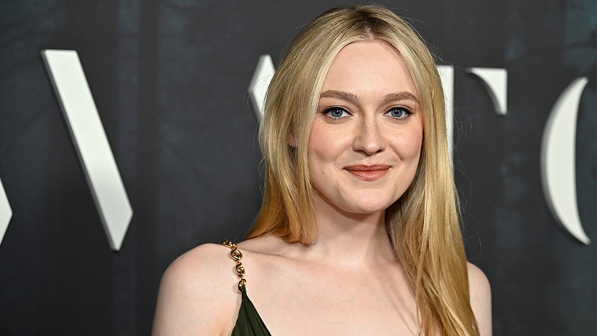 Dakota Fanning sorri suavemente no tapete em um vestido verde