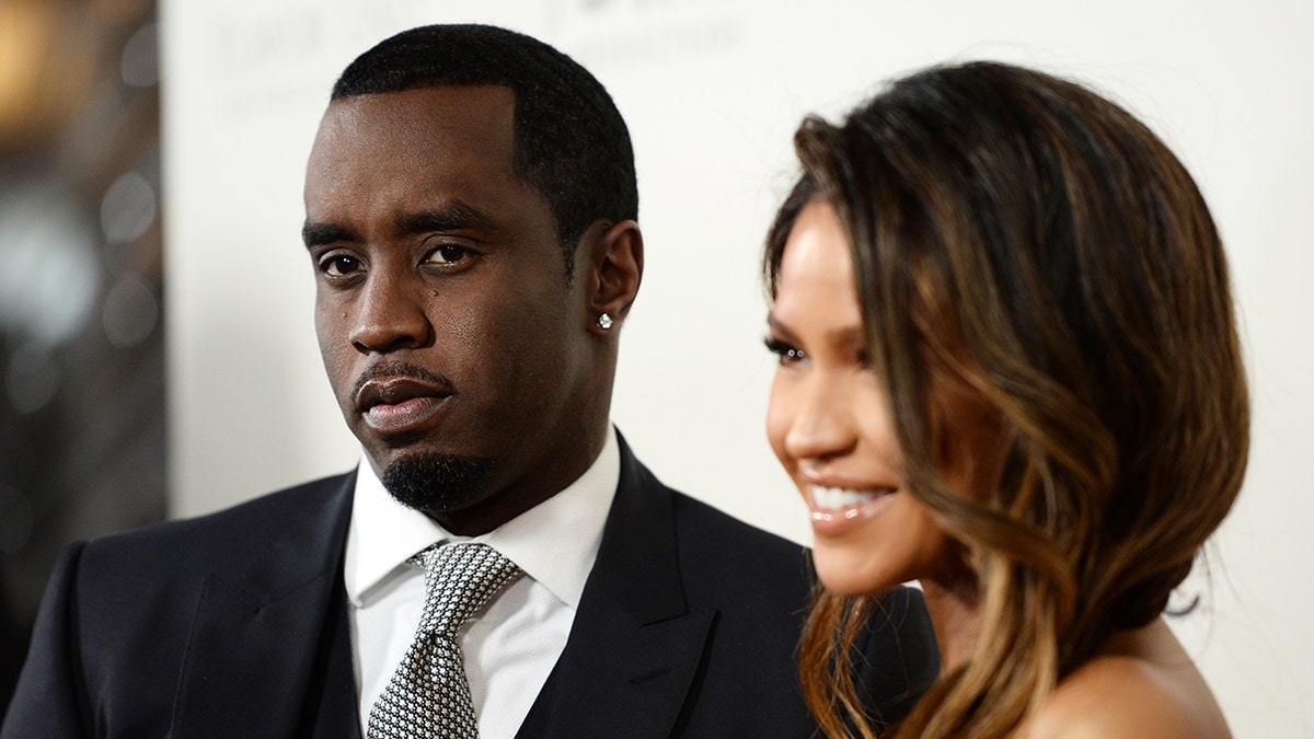 Sean Diddy Combs wears black suit with tie next to Cassie Ventura.