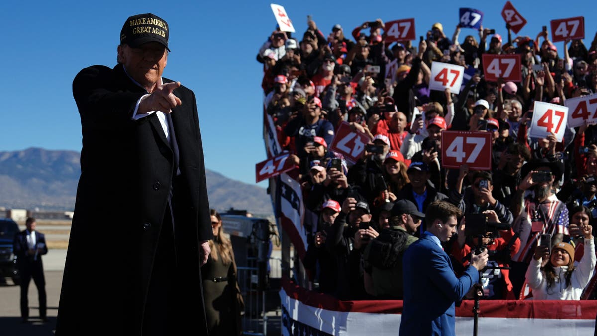 Donald Trump points his finger at the rally, with the crowd behind him to the right