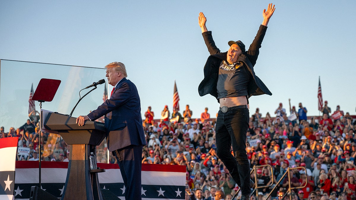 Elon Musk jumps in the air while Donald Trump stands at the podium