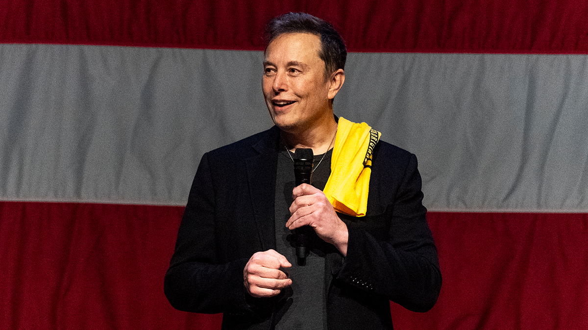 Elon Musk on stage with the US flag behind him