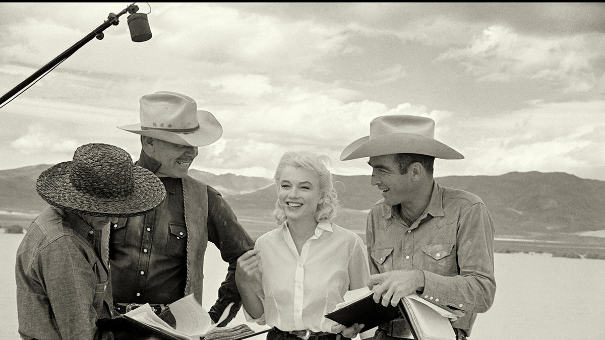 Marilyn Monroe sonriendo con el reparto de Los inadaptados