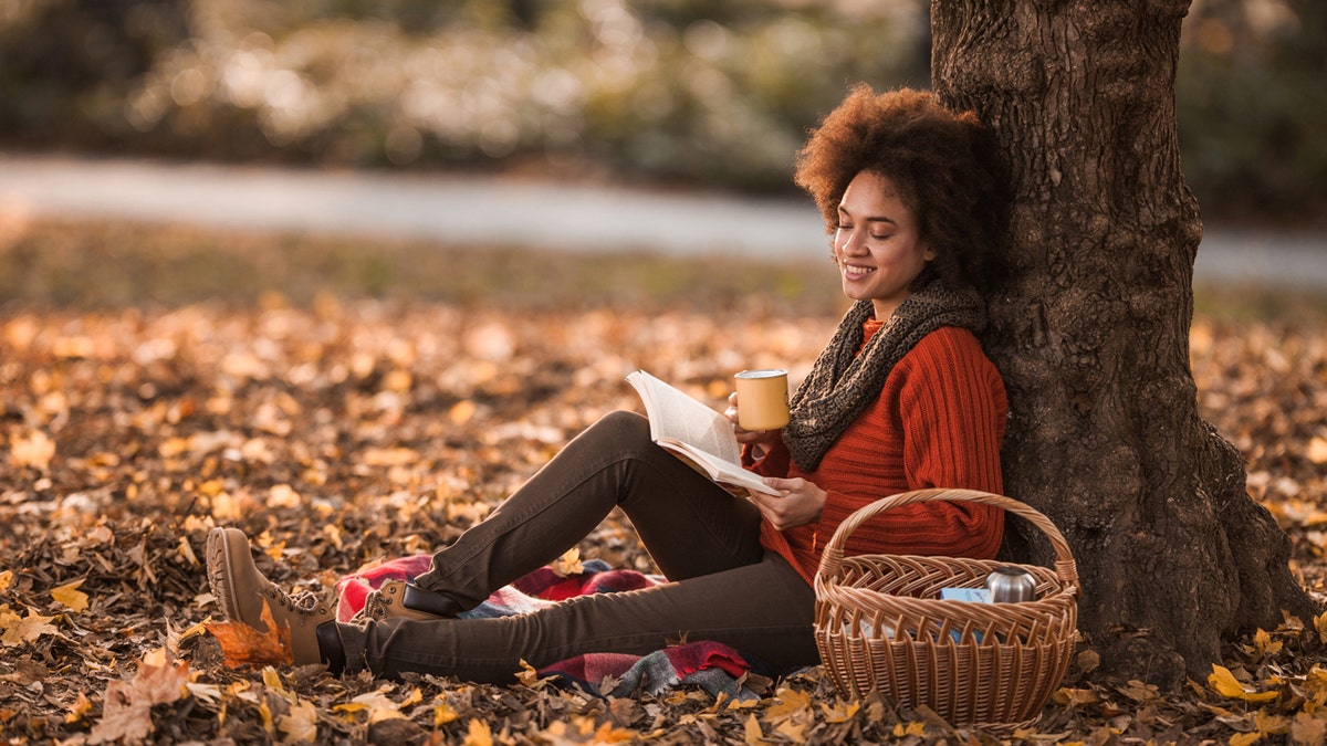 Una mujer leyendo un libro en otoño