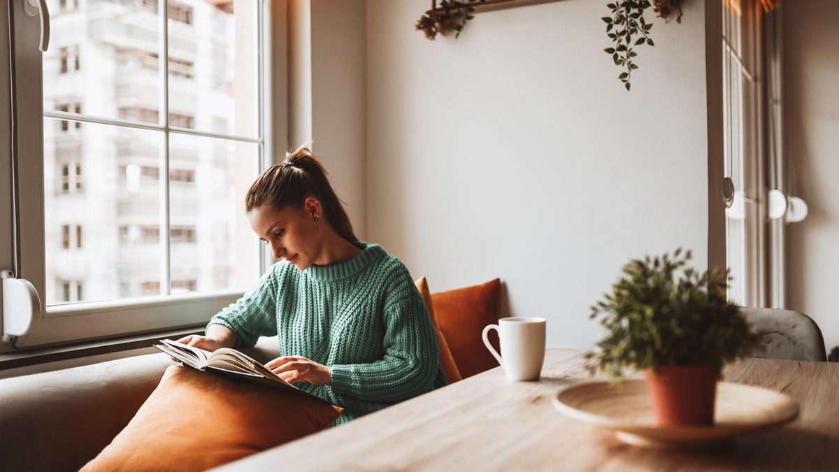 Una mujer leyendo un libro en casa