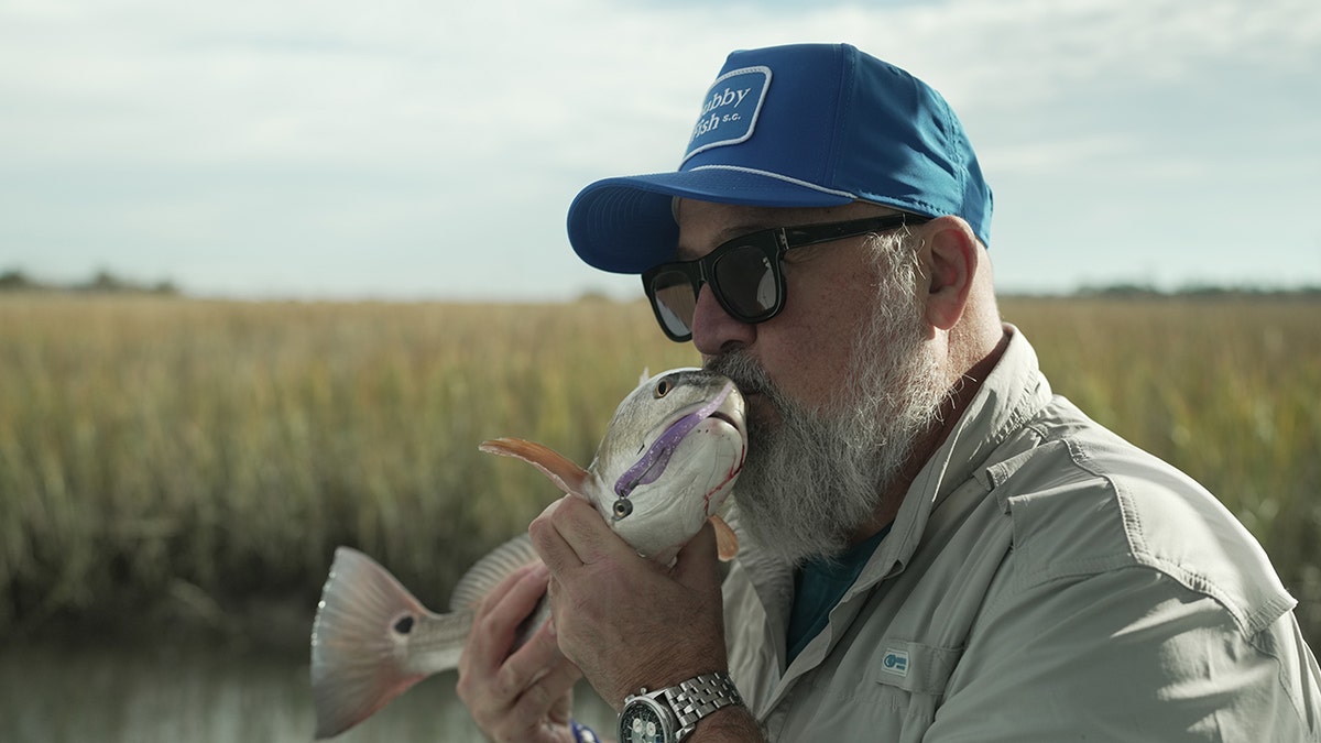 Andrew Zimmern kisses a fish he caught.