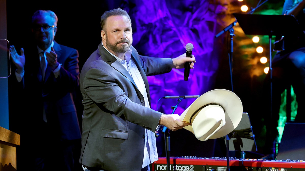 Garth Brooks se cuelga el sombrero vaquero como si acabara de quitárselo mientras está en el escenario