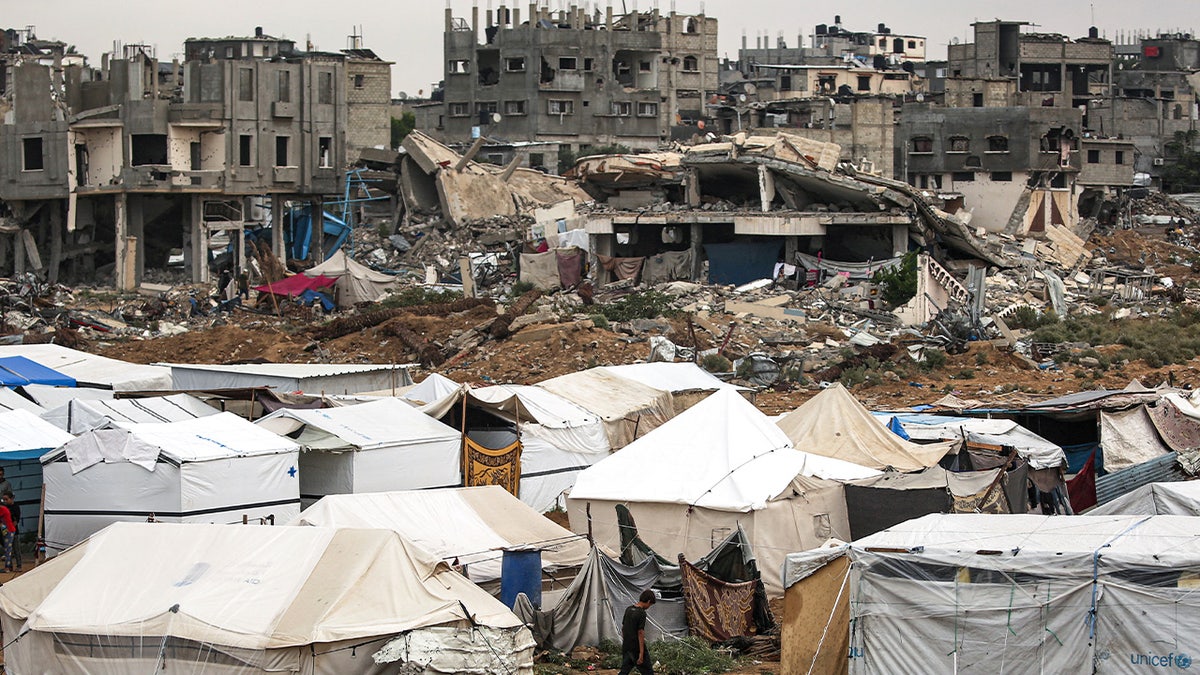 tents in foreground, bombed out buildings in background