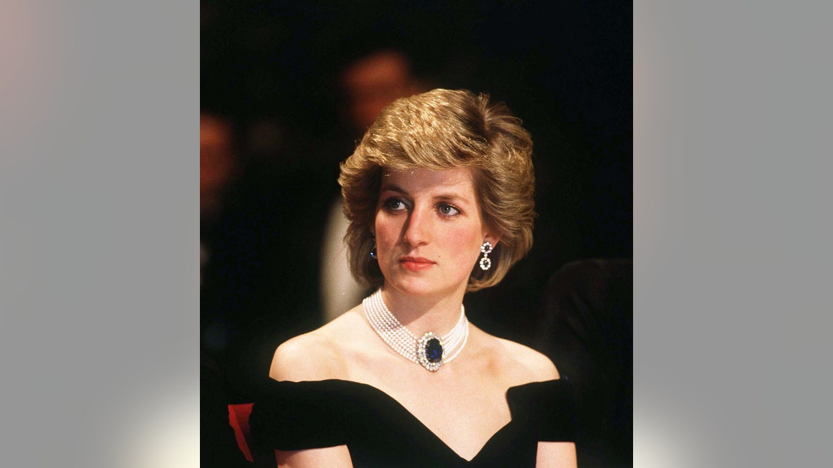 A close-up of Princess Diana wearing a black off-the-shoulder dress with jewels.