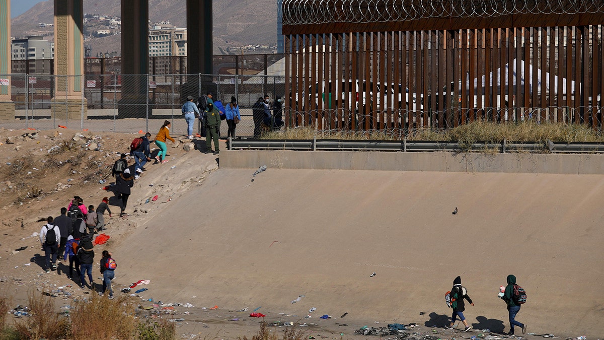 Migrants line up at the border wall