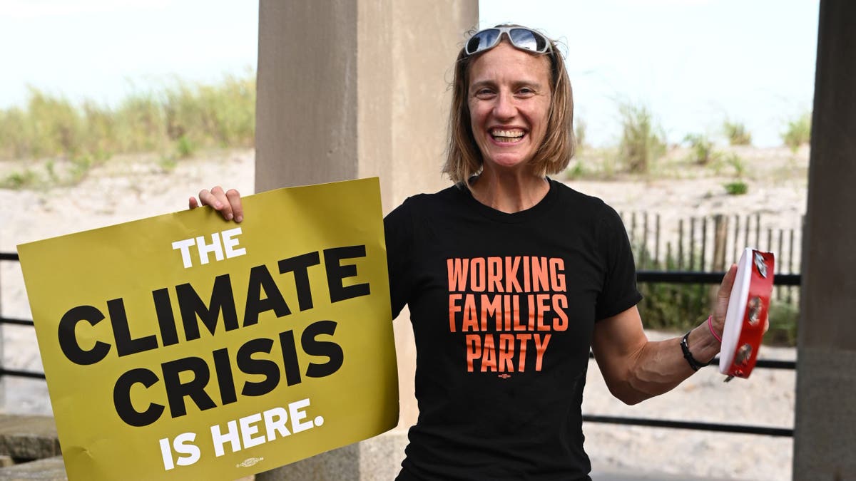 Altman holds the climate crisis sign and wears a Working Families Party shirt