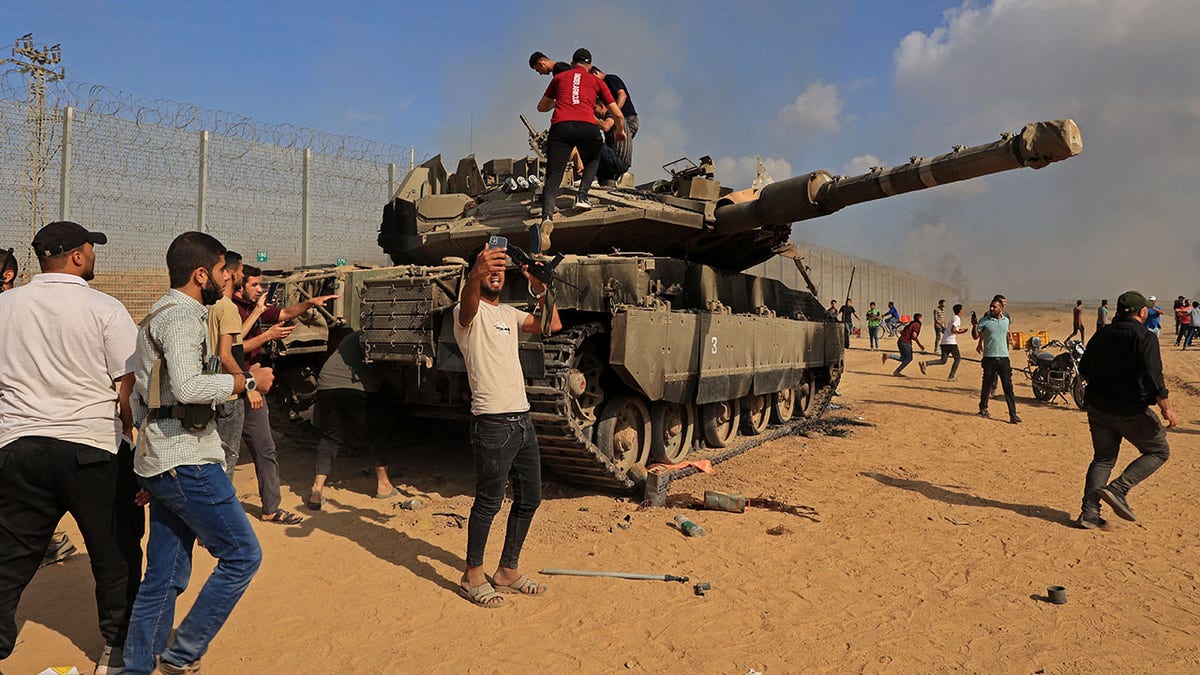 Palestinians adjacent an Israeli tank