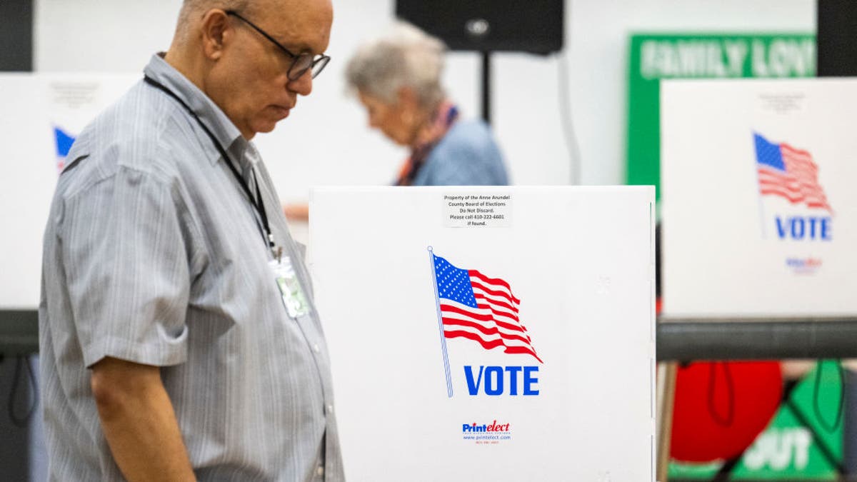 Poll workers from the Maryland Board of Elections walk past empty booths during the Maryland primary elections