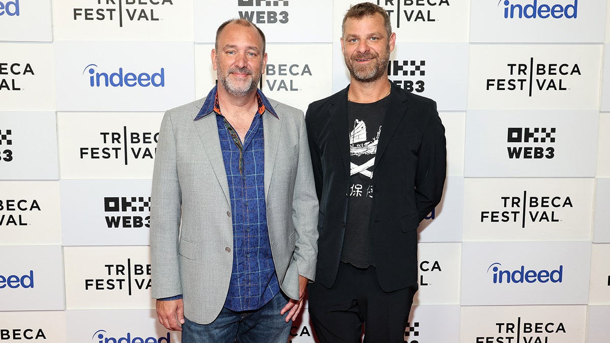 Trey Parker and Matt Stone posing on a red carpet.