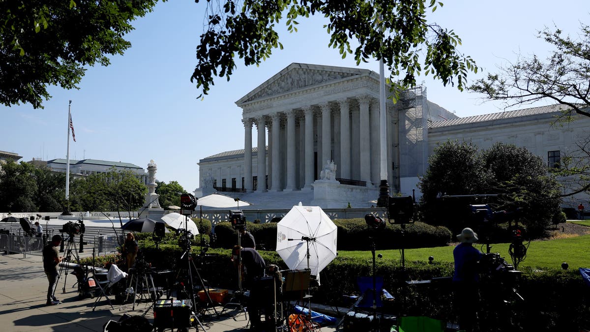 Reporters work outside the U.S. Supreme Court building in Washington, DC. (Photo by Anna Chanmemaker/Getty Images)