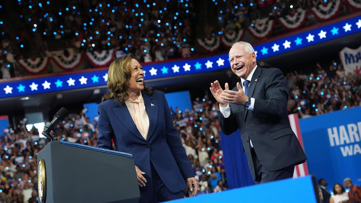 Kamala Harris y Tim Walz sonríen y saludan en un mitin