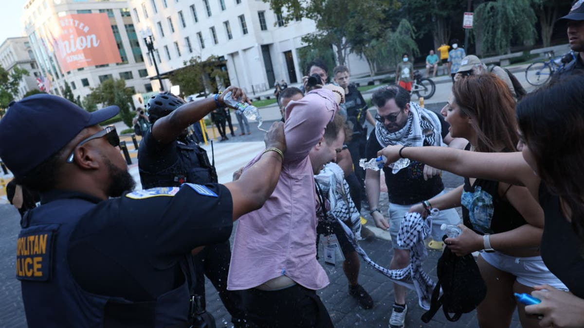 La policía ayuda a un hombre que se prendió fuego mientras la gente se manifiesta para conmemorar un año de la guerra entre Hamás e Israel frente a la Casa Blanca en Washington, DC, el 5 de octubre de 2024.