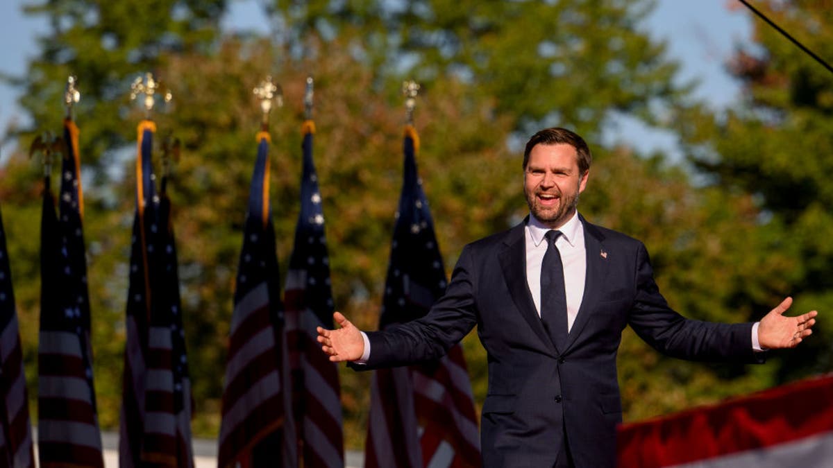 JD Vance with arms extended, flags down  him