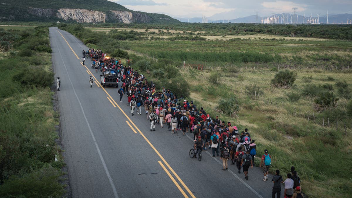 Aerial photo of a large group of migrants walking along a desert road