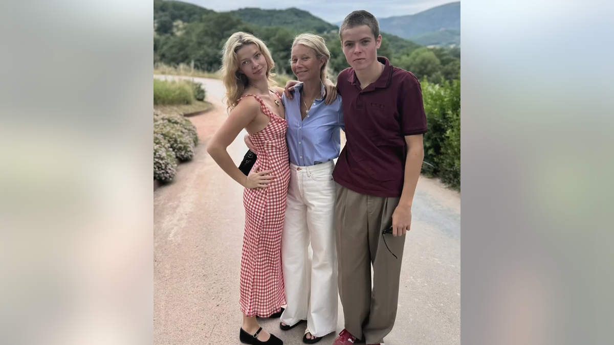 Apple Martin successful  a reddish  formal  poses with parent  Gwyneth Paltrow successful  a bluish  apical  and achromatic  pants and lad   Moses successful  a reddish  garment  and brownish  pants