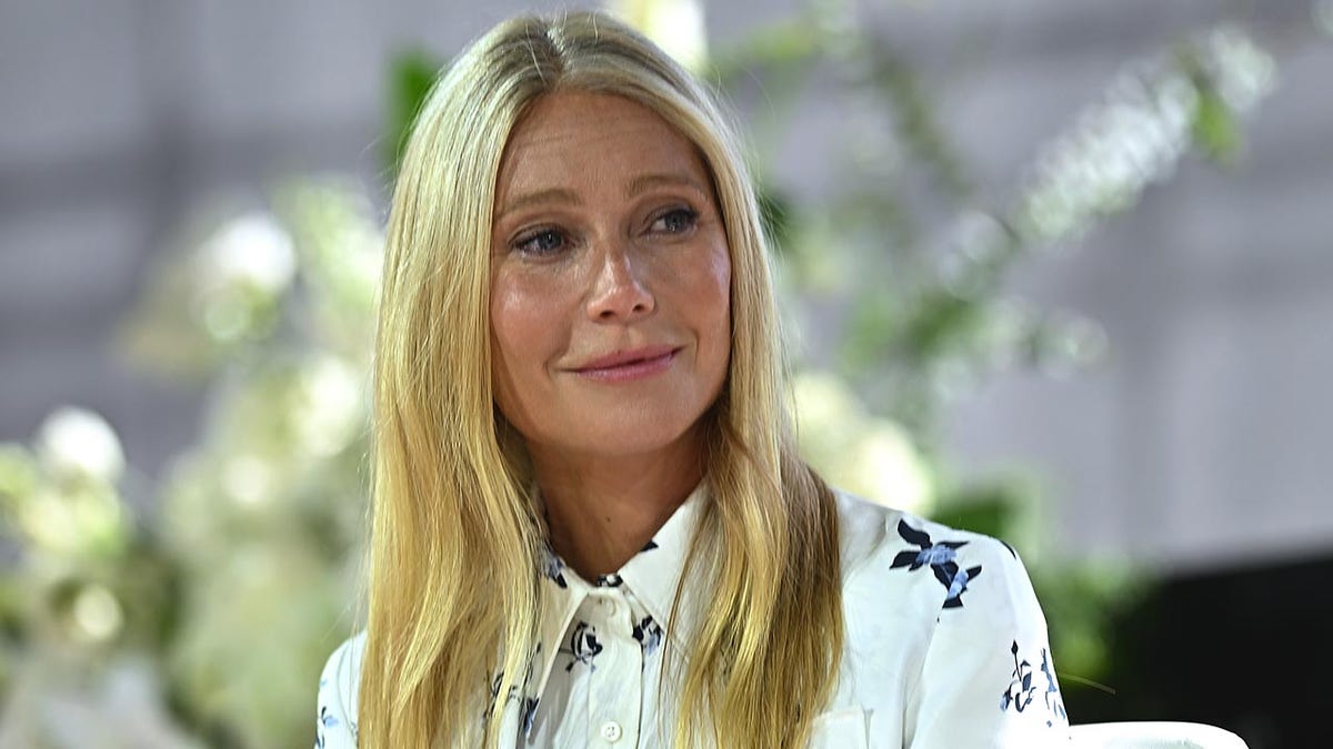 Gwyneth Paltrow successful a achromatic patterned blouse looks to her left