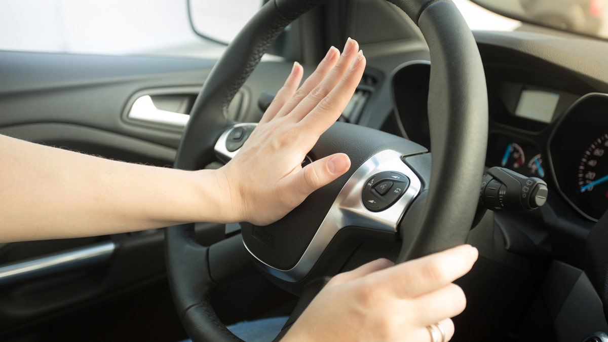 Una persona tocando la bocina de un auto.