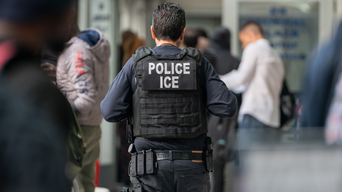 ICE agent seen from behind in POLICE jacket 