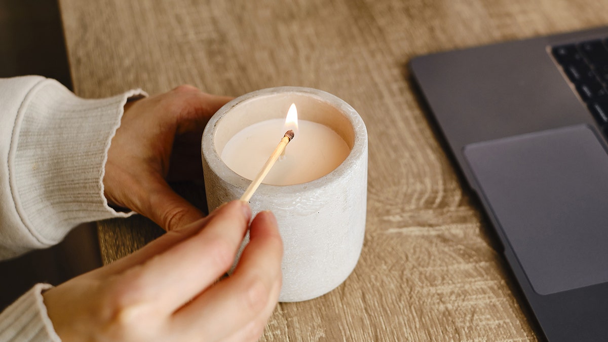 Girl lights candle astatine  desk