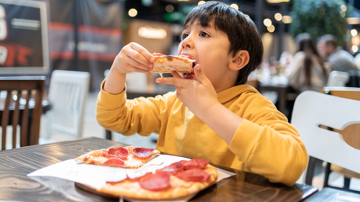 Niño pequeño comiendo pizza en un restaurante