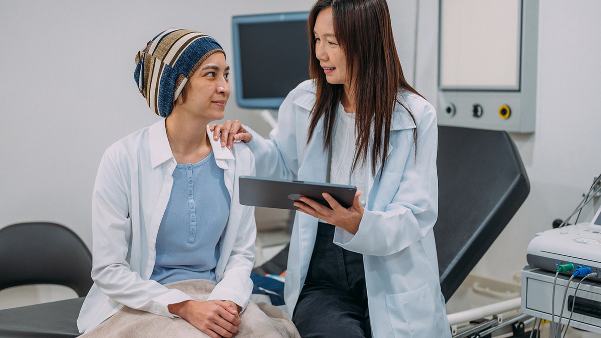 Una ginecóloga hablando con su paciente sobre la concientización sobre el cáncer de cuello uterino y los resultados de las pruebas en una tableta electrónica.