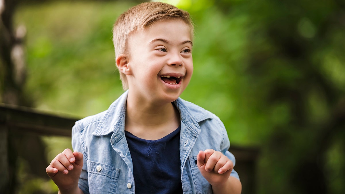 little lad  with down   syndrome playing successful  a park