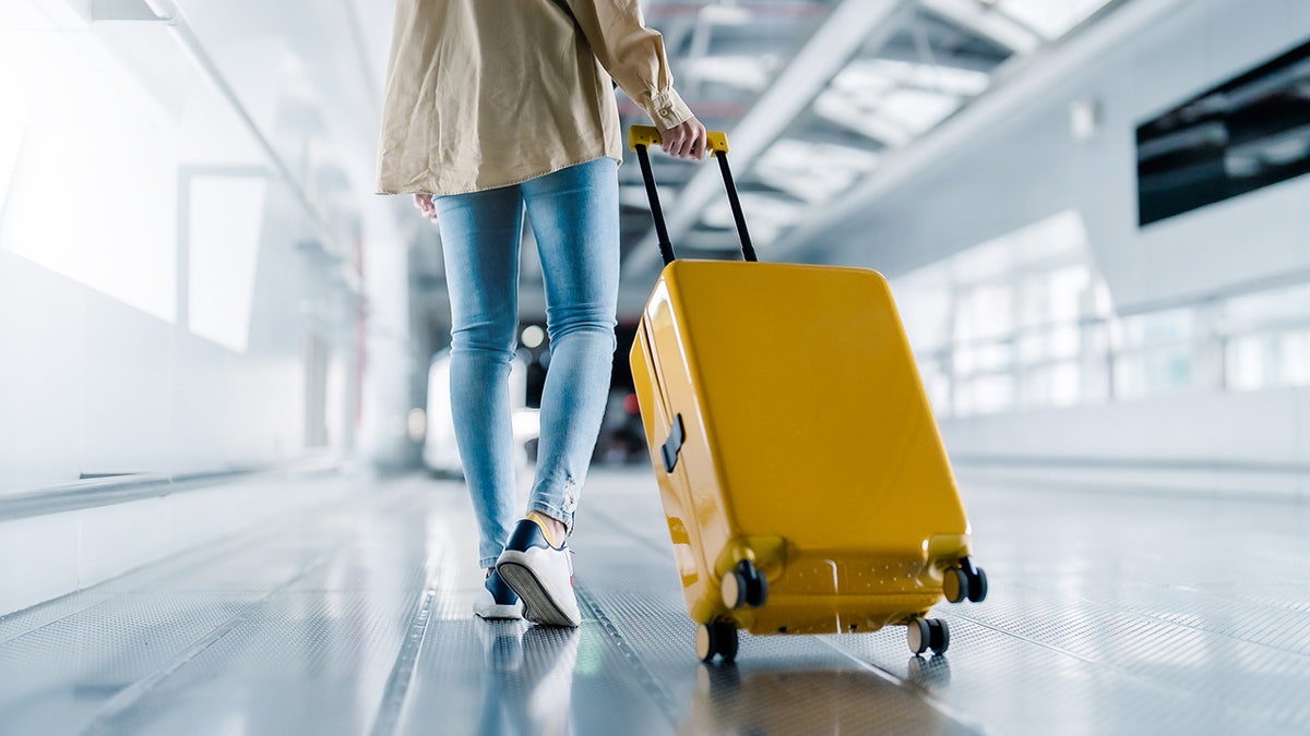 personne traînant des bagages à l'aéroport